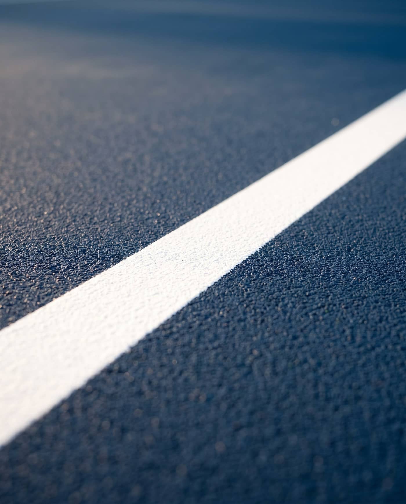 Close-up of a crisp white line on a navy court surface