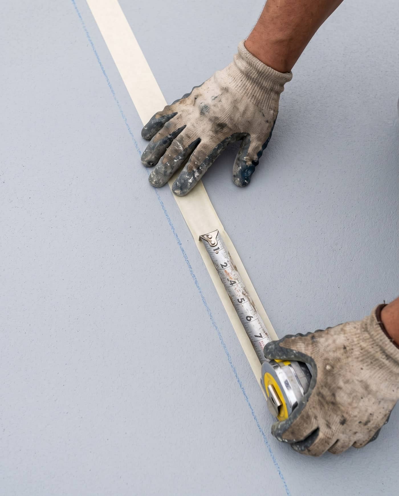 Hands taping a straight court line before it is painted