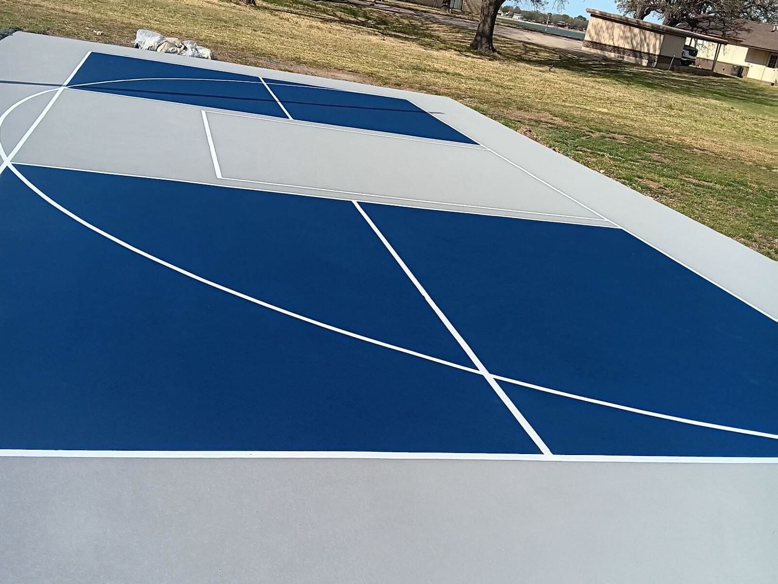 Blue and light gray multi-use court with pickleball and basketball lines