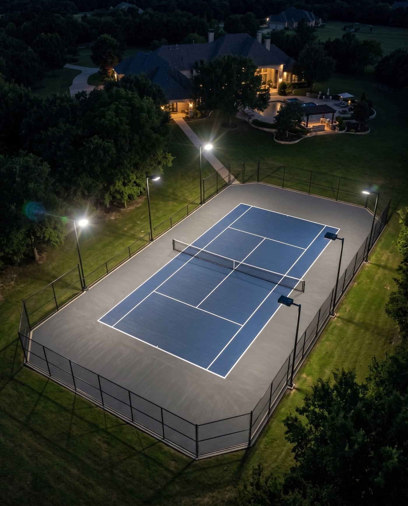 Tennis court under lights at night, seen from the corner